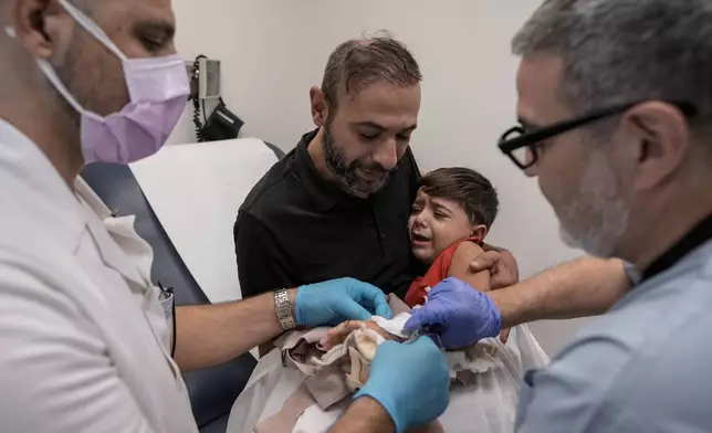 Hassan Mikdad, holds his son Hussein Mikdad, 4, who was injured on Oct. 2 in an Israeli airstrike at a densely-populated neighborhood south of Beirut, during a check up by his doctor at the American University of Beirut Medical Center (AUBMC), in Beirut, Lebanon, Tuesday, Nov. 5, 2024. (AP Photo/Bilal Hussein)