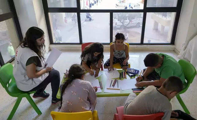 A Doctor's Without Borders counselor, left, talks to displaced children during a mental healthcare session in an empty building complex housing them, in Beirut, Lebanon, Wednesday, Oct. 9, 2024. (AP Photo/Bilal Hussein)