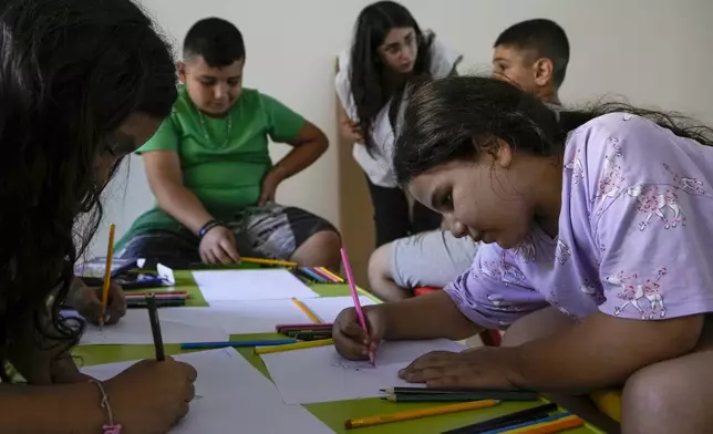 Displaced children draw during a mental healthcare session organized by Doctors Without Borders in an empty building complex housing them, in Beirut, Lebanon, Wednesday, Oct. 9, 2024. (AP Photo/Bilal Hussein)