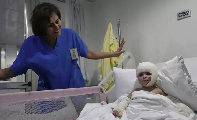 A nurse stands next of Ivana Skakye, 2, a Lebanese girl who is suffering from third-degree burns over 40 percent of her body following an Israeli airstrike last September near their home in Deir Qanoun al Nahr a village in south Lebanon, as she lies on a bed at the Geitaoui hospital where she is receiving treatment, in Beirut, Lebanon, Tuesday, Oct. 29, 2024. (AP Photo/Hussein Malla)