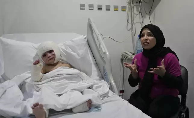 Fatima Zayoun, right, speaks during an interview with The Associated Press as she sits next to her daughter Ivana Skakye, 2, who is suffering from third-degree burns over 40 percent of her body following an Israeli airstrike last September near their home in Deir Qanoun al Nahr a village in south Lebanon, at the Geitaoui hospital where she is receiving treatment, in Beirut, Lebanon, Tuesday, Oct. 29, 2024. (AP Photo/Hussein Malla)