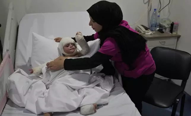 Fatima Zayoun, covers her daughter Ivana Skakye, 2, who is suffered for third-degree burns over 40 percent of her body following an Israeli airstrike last September near their home in Deir Qanoun al Nahr a village in south Lebanon, as she lies on the bed at the Lebanese hospital Geitaoui where she is receiving treatment, in Beirut, Lebanon, Tuesday, Oct. 29, 2024. (AP Photo/Hussein Malla)