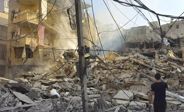 A resident films the site of an Israeli airstrike in Dahiyeh, Beirut, Lebanon, Wednesday, Nov. 13, 2024. (AP Photo/Hassan Ammar)