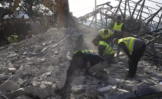 Rescue workers search for victims under the rubble of a destroyed house hit in an Israeli airstrike, in Aalmat village, northern Lebanon, Sunday, Nov. 10, 2024. (AP Photo/Hassan Ammar)