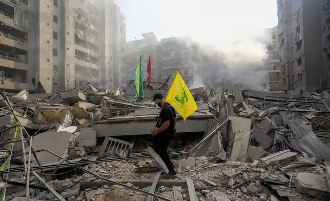 A man carries a Hezbollah flag as he walks on the rubble of his destroyed apartment following an Israeli airstrike in Dahiyeh, Beirut, Lebanon, Friday, Nov. 1, 2024. (AP Photo/Hassan Ammar)