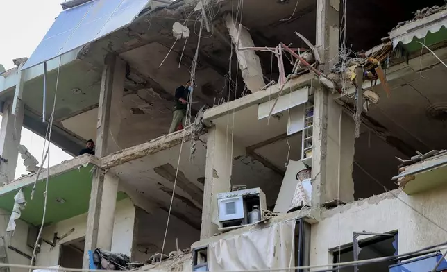 People inspect a destroyed building hit in an Israeli airstrike, in the southern port city of Sidon, Lebanon, Sunday, Nov. 3, 2024. (AP Photo/Mohammed Zaatari)