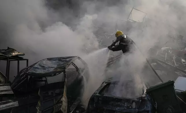 A civil defense worker extinguishes a fire as smoke rises from the site of an Israeli airstrike in Dahiyeh, Beirut, Lebanon, Friday, Nov. 1, 2024. (AP Photo/Hassan Ammar)