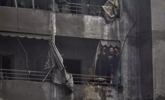 A man shouts slogans against Israel as he stands on the balcony of his damaged apartment at the site of an Israeli airstrike in Dahiyeh, Beirut, Lebanon, Friday, Nov. 1, 2024. (AP Photo/Hassan Ammar)