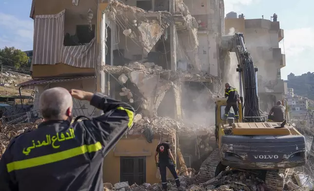 Rescue workers use an excavator to remove the rubble of a destroyed building that was hit Tuesday night in an Israeli airstrike, as they search for victims in Barja, Lebanon, Wednesday, Nov. 6, 2024. (AP Photo/Hassan Ammar)