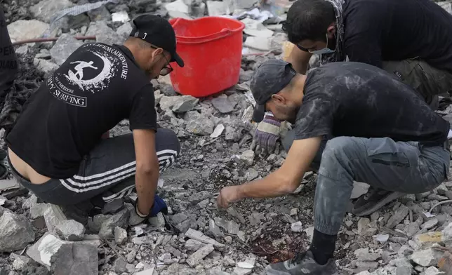 Rescue workers search for victims under the rubble of a destroyed house hit in an Israeli airstrike, in Aalmat village, northern Lebanon, Sunday, Nov. 10, 2024. (AP Photo/Hassan Ammar)