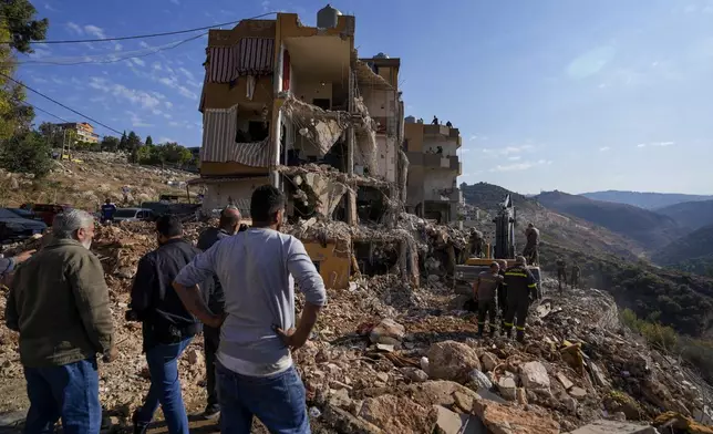 Rescue workers use an excavator to remove the rubble of a destroyed building hit in an Israeli airstrike on Tuesday night, as they search for victims in Barja, Lebanon, Wednesday, Nov. 6, 2024. (AP Photo/Hassan Ammar)