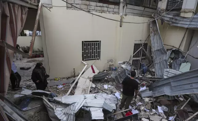 People inspect a destroyed building hit in an Israeli airstrike, in the southern port city of Sidon, Lebanon, Sunday, Nov. 3, 2024. (AP Photo/Mohammed Zaatari)