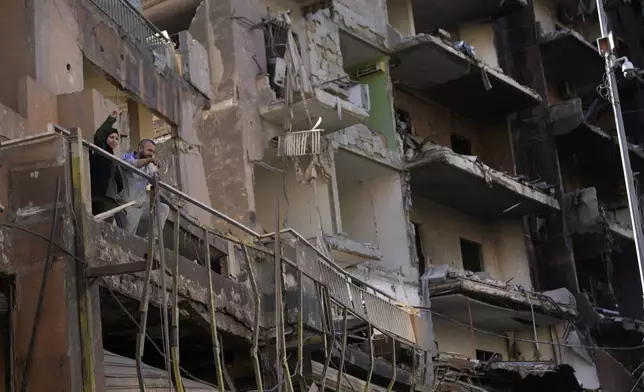 Residents stand on their apartment balcony at a building that was destroyed by an Israeli airstrike in Dahiyeh, in the southern suburb of Beirut, Lebanon, Monday, Nov. 11, 2024. (AP Photo/Hussein Malla)