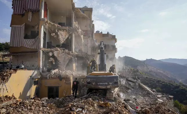 Rescue workers use excavators to remove the rubble of a destroyed building that was hit Tuesday night in an Israeli airstrike, as they search for victims in Barja, Lebanon, Wednesday, Nov. 6, 2024. (AP Photo/Hassan Ammar)