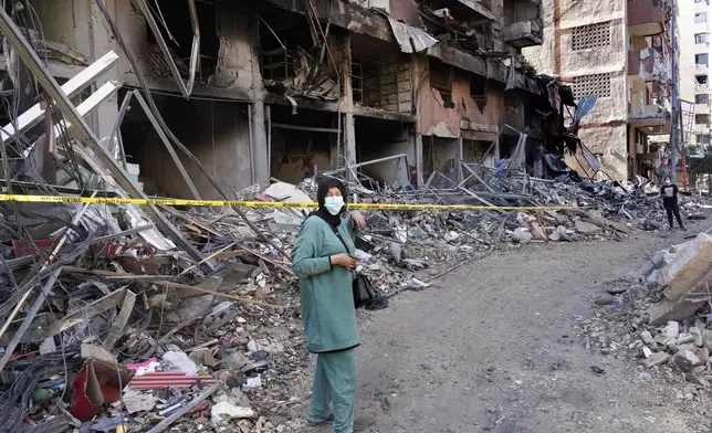 A woman stands in front of a building that was destroyed by an Israeli airstrike in Dahiyeh, in the southern suburb of Beirut, Lebanon, Monday, Nov. 11, 2024. (AP Photo/Hussein Malla)