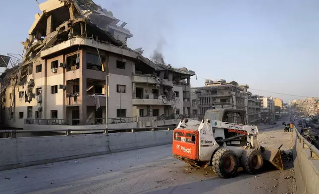 A municipality worker uses a skid steer loader to reopen a bridge closed by the rubble of a destroyed building that was hit by an Israeli airstrike on Dahiyeh, in the southern suburb of Beirut, Lebanon, Friday, Nov. 1, 2024. (AP Photo/Hussein Malla)