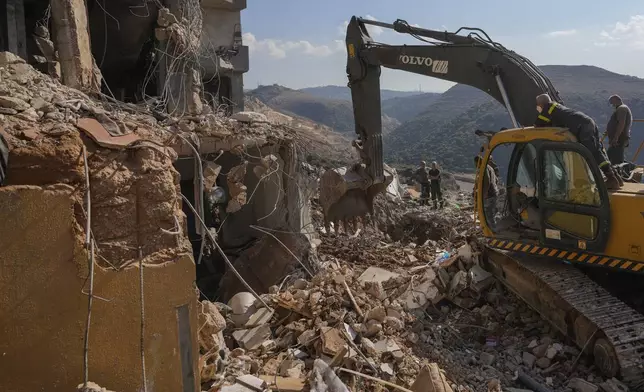 Rescue workers use an excavator to remove the rubble of a destroyed building hit in an Israeli airstrike on Tuesday night, as they search for victims in Barja, Lebanon, Wednesday, Nov. 6, 2024. (AP Photo/Hassan Ammar)