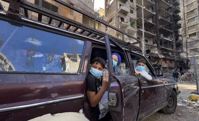 Children sit in a car as they wait their parents, who are collecting belongings from their house, which was destroyed by an Israeli airstrike in Dahiyeh, in the southern suburb of Beirut, Lebanon, Monday, Nov. 11, 2024. (AP Photo/Hussein Malla)