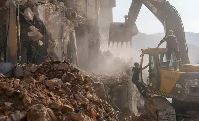 Rescue workers use an excavator to remove the rubble of a destroyed building hit in an Israeli airstrike on Tuesday night, as they search for victims in Barja, Lebanon, Wednesday, Nov. 6, 2024. (AP Photo/Hassan Ammar)