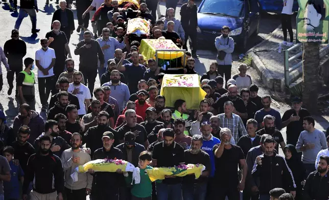 Mourners carry the bodies of victims who were killed on Monday evening in an Israeli airstrike, during a mass funeral in Saksakiyeh village, south Lebanon, Wednesday, Nov. 13, 2024. (AP Photo/Mohammed Zaatari)