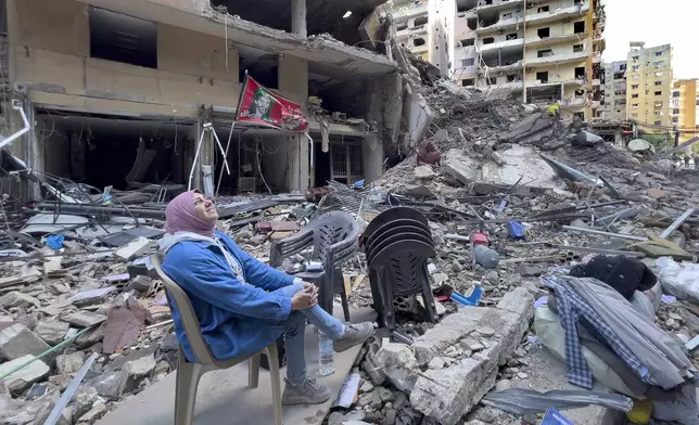 A woman sits on the rubble as she looks to a building destroyed by an Israeli airstrike in Dahiyeh, in the southern suburb of Beirut, Lebanon, Monday, Nov. 11, 2024. (AP Photo/Hussein Malla)