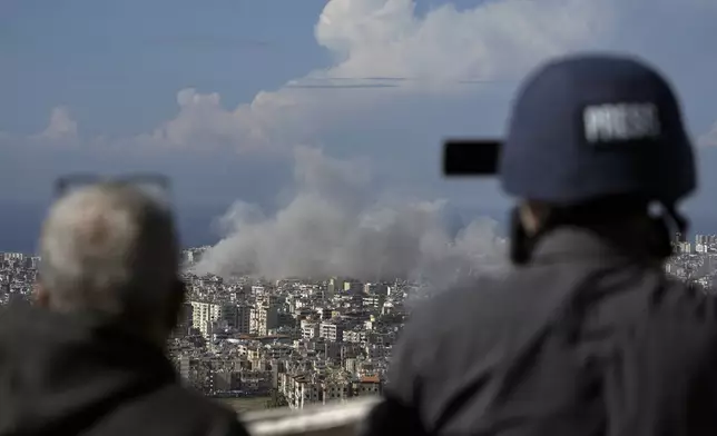 Journalists document as smoke rises after an Israeli airstrike on Dahiyeh, in the southern suburb of Beirut, Lebanon, Tuesday, Nov. 12, 2024. (AP Photo/Bilal Hussein)