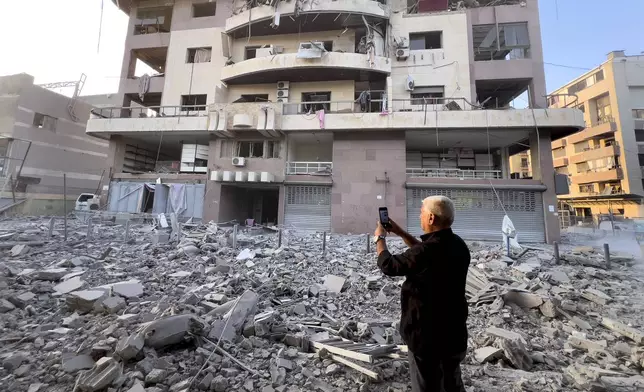 A man takes pictures by his mobile phone of a destroyed building hit by an Israeli airstrike on Dahiyeh, in the southern suburb of Beirut, Lebanon, early Friday, Nov. 1, 2024. (AP Photo/Hussein Malla)