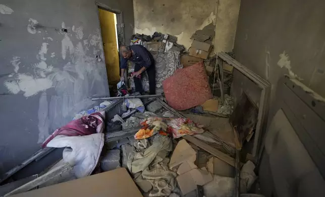 A resident of a building damaged in an Israeli airstrike on Tuesday night, returns to collect his family's belongings in Barja, Lebanon, Wednesday, Nov. 6, 2024. (AP Photo/Hassan Ammar)