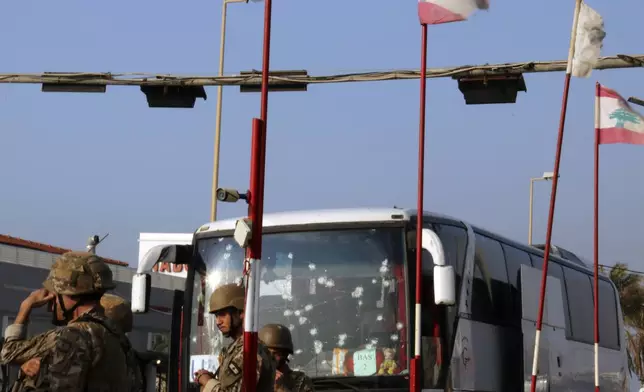 In this handout photo, Lebanese army soldiers stand guard next to a damaged bus of the Malaysian U.N. peacekeepers at the site of an Israeli strike hit a car, in the southern port city of Sidon, Lebanon, Thursday, Nov. 7, 2024. (AP Photo)