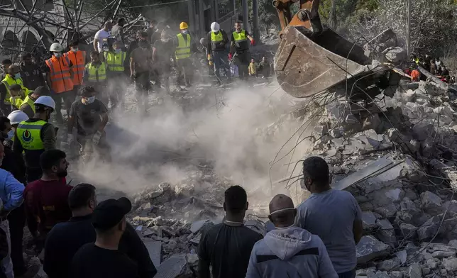 Rescue workers and people search for victims under the rubble of a destroyed house hit in an Israeli airstrike, in Aalmat village, northern Lebanon, Sunday, Nov. 10, 2024. (AP Photo/Hassan Ammar)