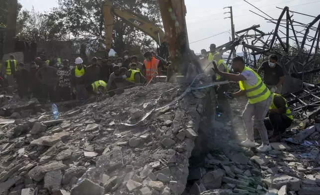 Rescue workers and people search for victims under the rubble of a destroyed house hit in an Israeli airstrike, in Aalmat village, northern Lebanon, Sunday, Nov. 10, 2024. (AP Photo/Hassan Ammar)