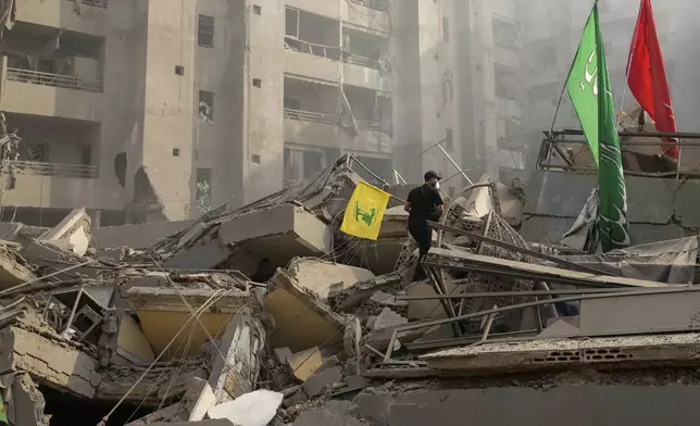 A man carries a Hezbollah flag as he walks on the rubble of his destroyed apartment following an Israeli airstrike in Dahiyeh, Beirut, Lebanon, Friday, Nov. 1, 2024. (AP Photo/Hassan Ammar)