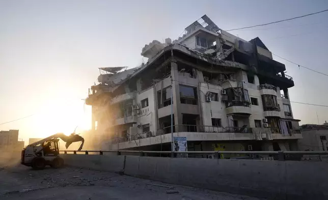 A municipality worker uses a skid steer loader to reopen a bridge closed by the rubble of a destroyed building that was hit by an Israeli airstrike on Dahiyeh, in the southern suburb of Beirut, Lebanon, Friday, Nov. 1, 2024. (AP Photo/Hussein Malla)