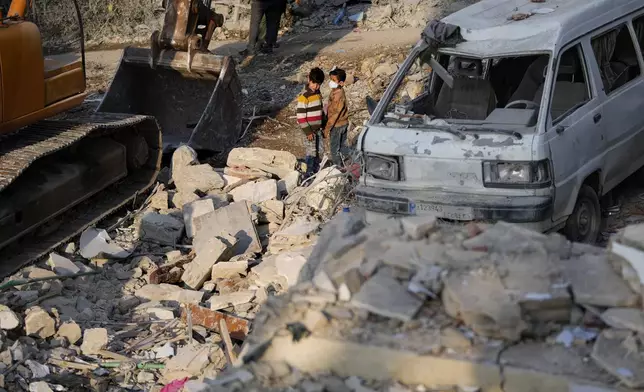 Two boys observe the site where an Israeli airstrike hit a house in Aalmat village, northern Lebanon, Sunday, Nov. 10, 2024. (AP Photo/Hassan Ammar)