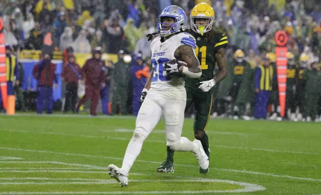 Detroit Lions running back Jahmyr Gibbs (26) scores a rushing touchdown past Green Bay Packers cornerback Eric Stokes during the second half of an NFL football game Sunday, Nov. 3, 2024, in Green Bay, Wis. (AP Photo/Matt Ludtke)