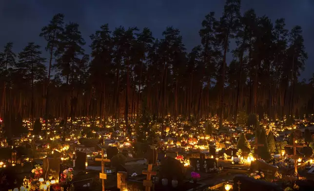 Candles are lit during All Saints Day at the cemetery in Vilnius, Lithuania, Friday, Nov. 1, 2024. (AP Photo/Mindaugas Kulbis)