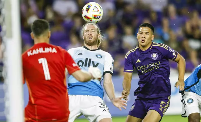 Charlotte FC defender Tim Ream, center, stops ball in front of teammate goalkeeper Kristijan Kahlina (1) as Orlando City midfielder César Araújo, right, looks to score during the first half of Game 3 of a first round MLS Cup playoff soccer match Saturday, Nov. 9, 2024, in Orlando, Fla. (AP Photo/Kevin Kolczynski)