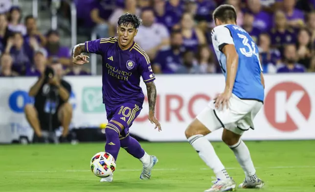 Orlando City forward Facundo Torres (10) brings the ball down pitch against Charlotte FC midfielder Andrew Privett, right, during the first half of Game 3 of a first round MLS Cup playoff soccer match Saturday, Nov. 9, 2024, in Orlando, Fla. (AP Photo/Kevin Kolczynski)