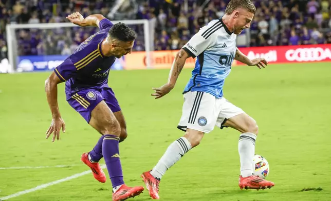 Charlotte FC midfielder Pep Biel, right, defends goal against Orlando City midfielder Martín Ojeda, left, during the first half of Game 3 of a first round MLS Cup playoff soccer match Saturday, Nov. 9, 2024, in Orlando, Fla. (AP Photo/Kevin Kolczynski)