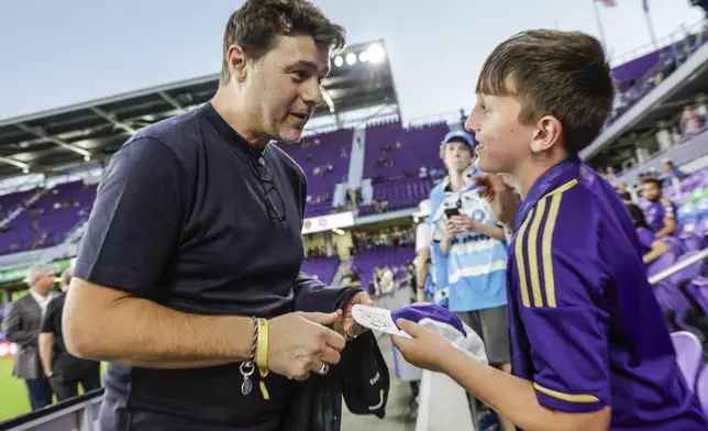 Team USA soccer Coach Mauricio Pochettino talks to 10-year-old fan Dylan McMahon before the Game 3 match between Orlando City and Charlotte FC in the first round MLS Cup playoff soccer match Saturday, Nov. 9, 2024, in Orlando, Fla. (AP Photo/Kevin Kolczynski)