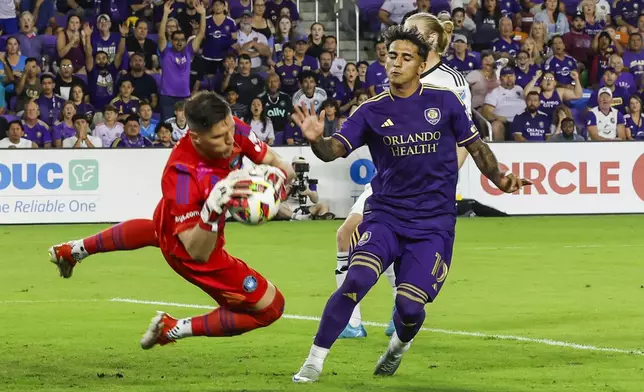 Charlotte FC goalkeeper Kristijan Kahlina, left, stops the ball kicked by Orlando City forward Facundo Torres, right, during the first half of Game 3 of a first round MLS Cup playoff soccer match Saturday, Nov. 9, 2024, in Orlando, Fla. (AP Photo/Kevin Kolczynski)