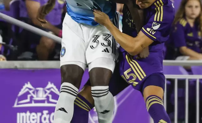 Charlotte FC forward Patrick Agyemang (33) and Orlando City defender Rodrigo Schlegel, right, fight over possession during the first half of Game 3 of a first round MLS Cup playoff soccer match Saturday, Nov. 9, 2024, in Orlando, Fla. (AP Photo/Kevin Kolczynski)