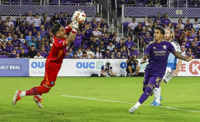 Charlotte FC goalkeeper Kristijan Kahlina, left, stops the ball kicked by Orlando City forward Facundo Torres, right, during the first half of Game 3 of a first round MLS Cup playoff soccer match Saturday, Nov. 9, 2024, in Orlando, Fla. (AP Photo/Kevin Kolczynski)