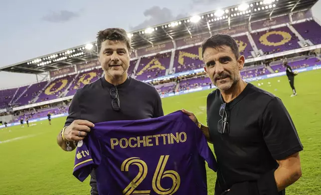 Team USA soccer Coach Mauricio Pochettino and MSL Commissioner Don Garber hold up Orlando City shirt showing Pochettino's name before the Game 3 match between Orlando City and Charlotte FC in the first round MLS Cup playoff soccer match Saturday, Nov. 9, 2024, in Orlando, Fla. (AP Photo/Kevin Kolczynski)