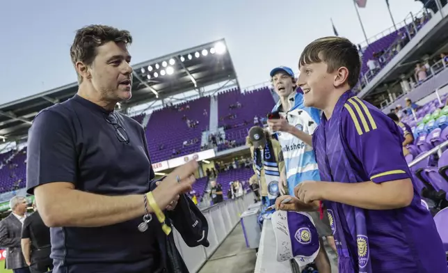 Team USA soccer Coach Mauricio Pochettino talks to 10-year-old fan Dylan McMahon before the Game 3 match between Orlando City and Charlotte FC in the first round MLS Cup playoff soccer match Saturday, Nov. 9, 2024, in Orlando, Fla. (AP Photo/Kevin Kolczynski)