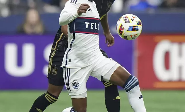 Vancouver Whitecaps' Fafa Picault, front left, and Los Angeles FC's Timothy Tillman, back, vie for the ball during the first half of Game 2 in the first round of the MLS Cup soccer playoffs in Vancouver, British Columbia, Sunday, Nov. 3, 2024. (Darryl Dyck/The Canadian Press via AP)