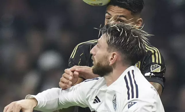 Vancouver Whitecaps' Tristan Blackmon, front, and Los Angeles FC's Denis Bouanga, top, vie for the ball during the first half of Game 2 in the first round of the MLS Cup soccer playoffs in Vancouver, British Columbia, Sunday, Nov. 3, 2024. (Darryl Dyck/The Canadian Press via AP)