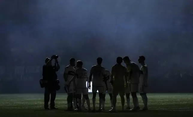 Vancouver Whitecaps players are silhouetted as smoke from pyrotechnics hangs in the air before Game 2 against Los Angeles FC in the first round of the MLS Cup soccer playoffs in Vancouver, British Columbia, Sunday, Nov. 3, 2024. (Darryl Dyck/The Canadian Press via AP)