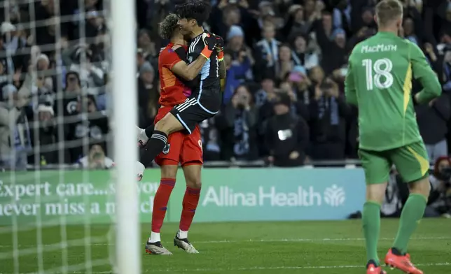 Minnesota United goalkeeper Dayne St. Clair, left, and forward Jeong Sang-Bin, center, embrace as they win a first-round soccer match of the MLS Cup playoffs in a penalty shoot out against Real Salt Lake in St. Paul, Minn., Saturday, Nov. 2, 2024. (AP Photo/Ellen Schmidt)