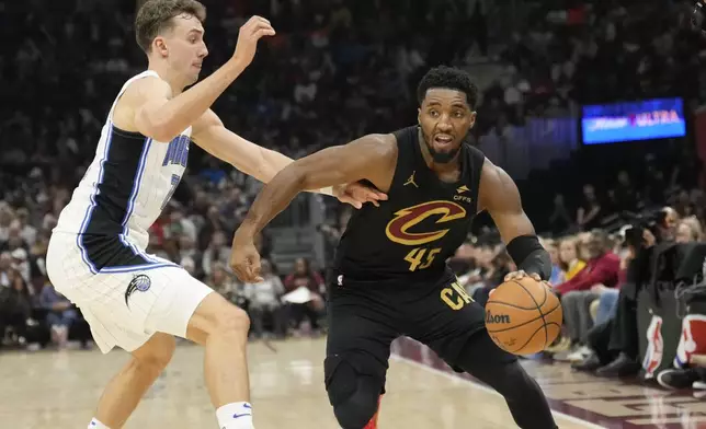 Cleveland Cavaliers guard Donovan Mitchell (45) drives past Orlando Magic forward Franz Wagner, left, in the first half of an NBA game, Friday, Nov. 1, 2024, in Cleveland. (AP PhotoSue Ogrocki)